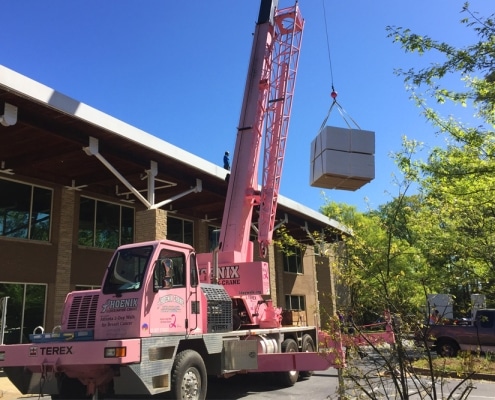 commercial-roofing-5 Pink crane lifting roofing materials to commercial site