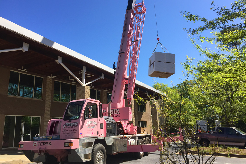 commercial-roofing-5 Pink crane lifting roofing materials to commercial site