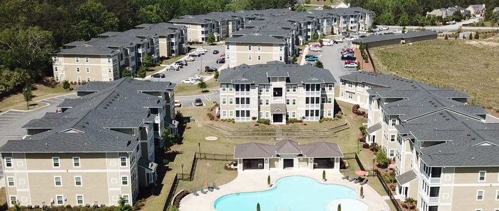 Aerial view of a large apartment complex in Atlanta, GA with well-maintained commercial roofing and a swimming pool