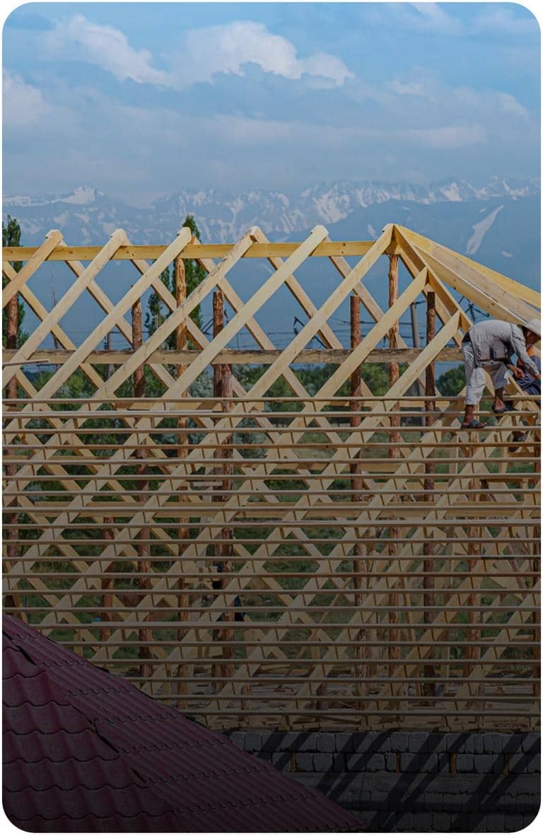 Crew member working on wood roof framing during logistics and staging setup of a commercial roofing project