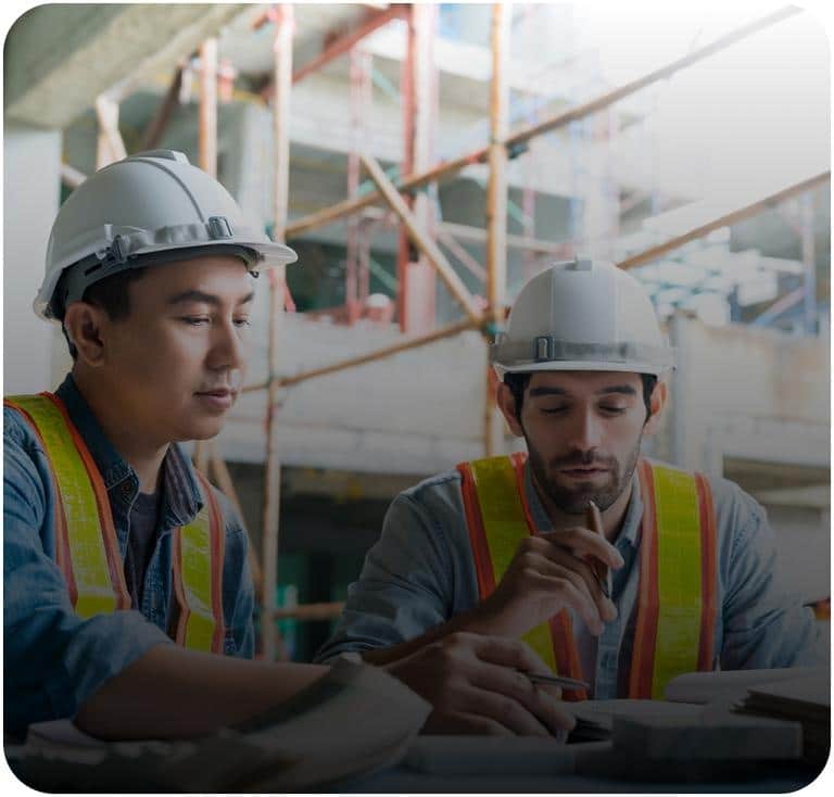 Two commercial roofing contractors reviewing daily project plans at an indoor job site