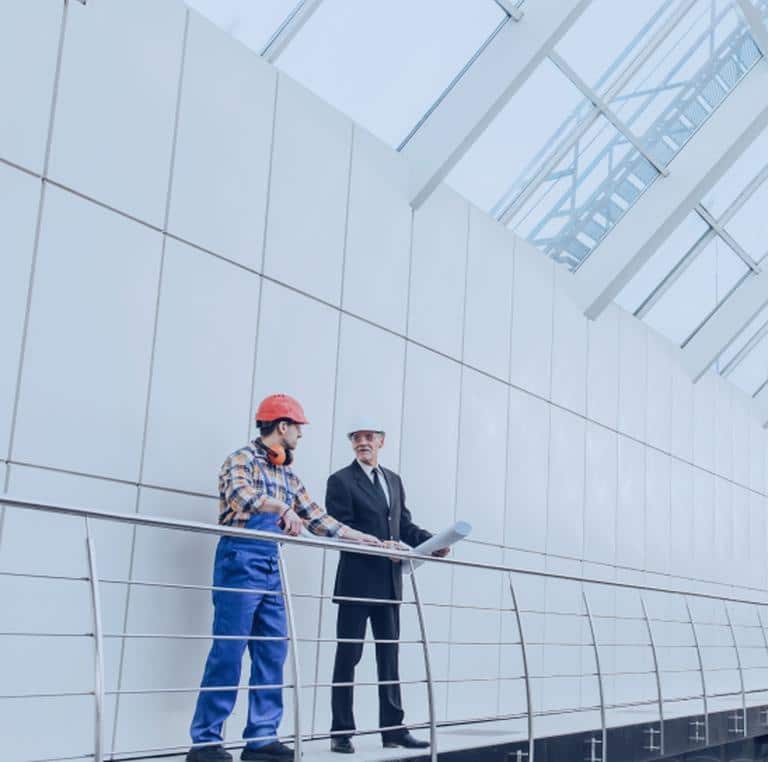 Two roofers performing final walkthrough and gutter inspection on completed metal commercial roof