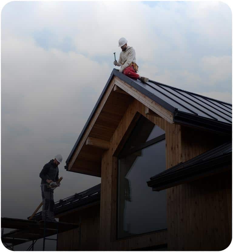 Two commercial roofing contractors installing a standing seam metal roof on a commercial building