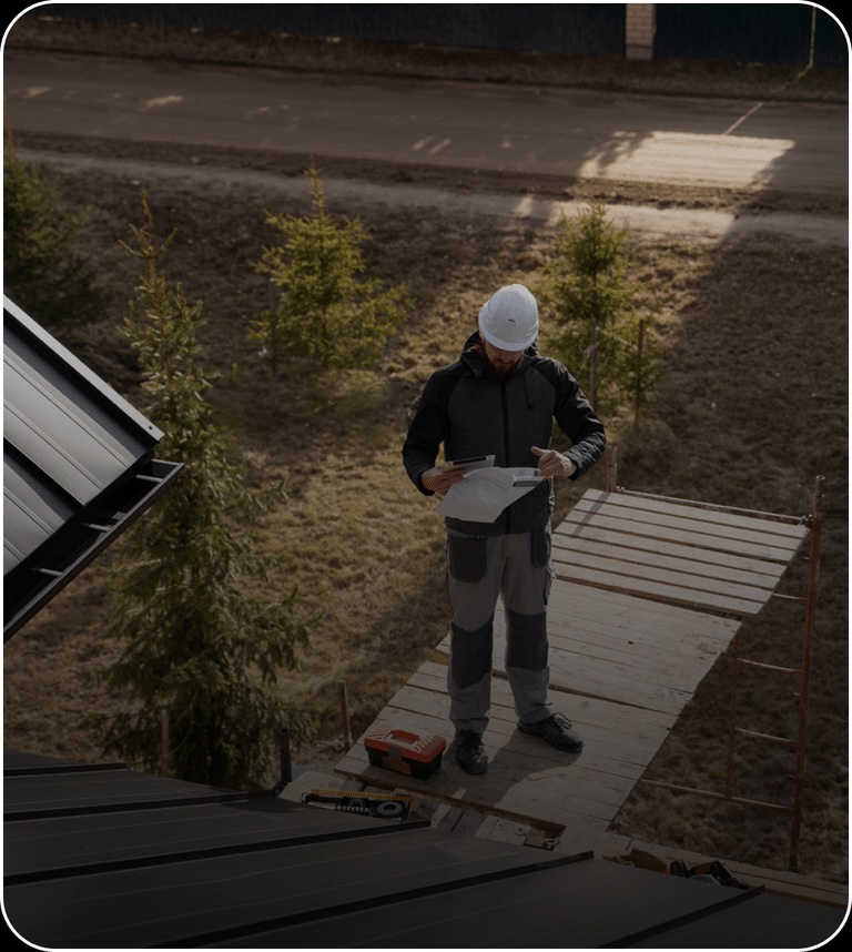 Commercial roofing contractor reviewing roof plans during pre-project assessment near standing seam metal roof