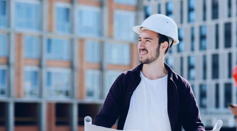Project manager overseeing a commercial roofing project with blueprints in hand at an active construction site