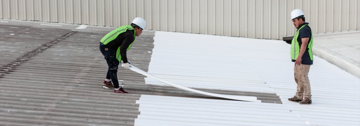 Academy Roofing crew installing a white single-ply membrane on a commercial roof