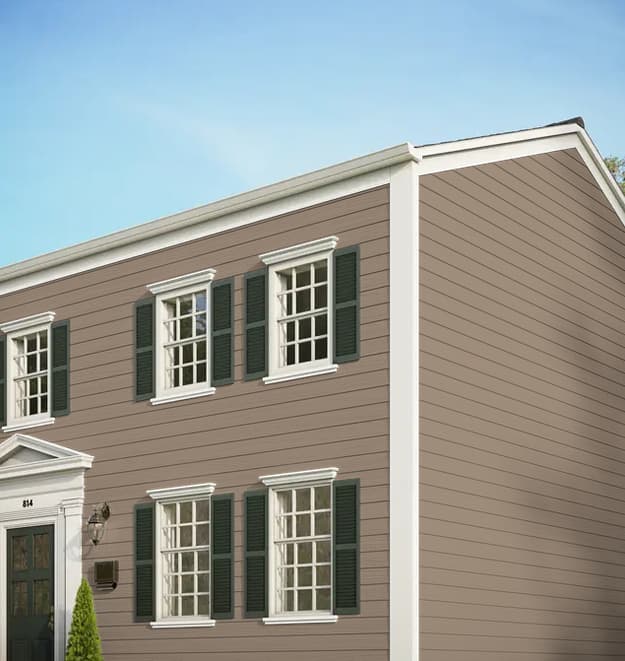 Two-story home featuring neutral taupe horizontal lap siding, white window trim, and dark green shutters.