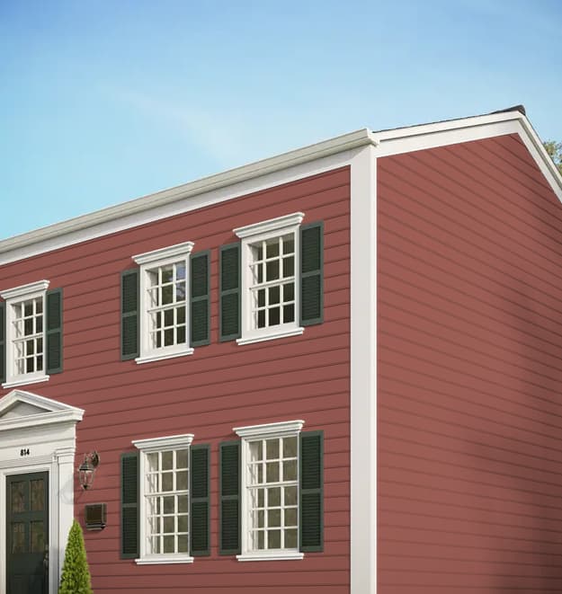 Traditional two-story home with red horizontal lap siding, white architectural trim, and dark green shutters.
